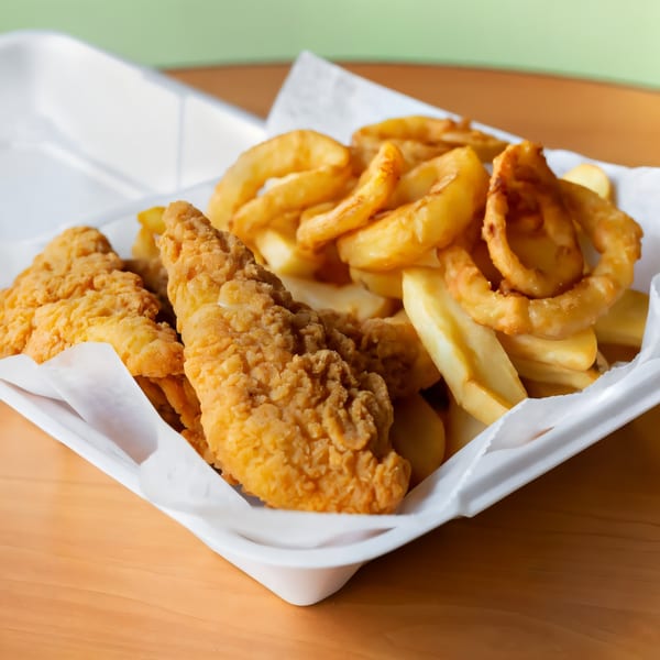Fried chicken tenders, french fries, and onion rings in a white takeout container.