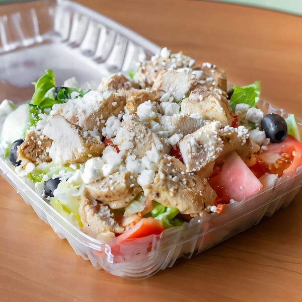 J&M Italian American Cuisine's grilled chicken salad with feta, olives, and tomatoes in a takeout container.