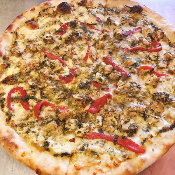 A J&M Italian American Cuisine pizza with chicken, red peppers, and pesto on a white sauce base.