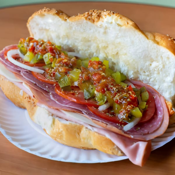 A J&M Italian American Cuisine sub sandwich with meats, cheese, tomatoes, onions, and relish.